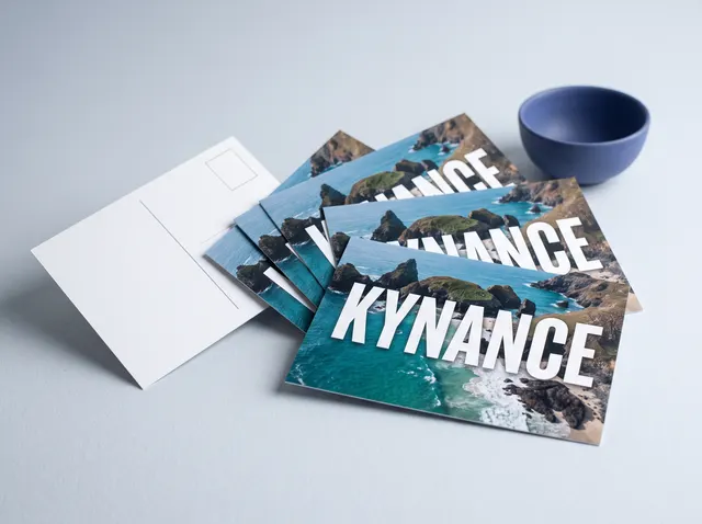 Kynance postcards with an aerial photo of a turquoise cove, one turned to show the back